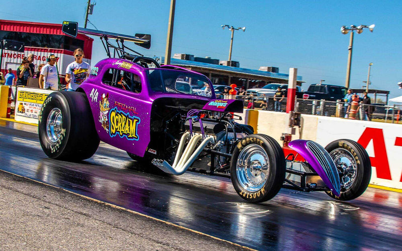 Boss Hog-equipped purple dragster launching at the drag strip